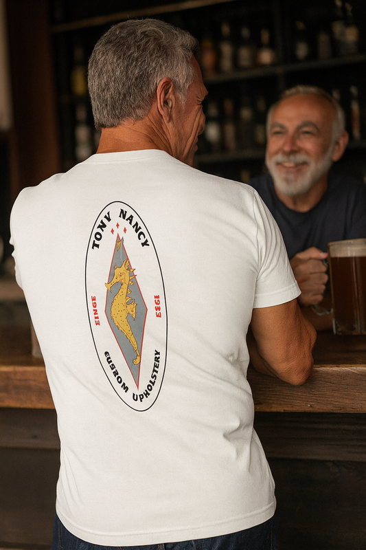 Man wearing a white bonspeed Tony Nancy t-shirt with a logo sitting at a bar.