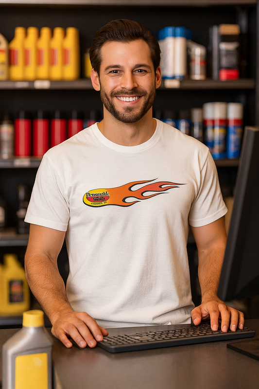 Man wearing a white bonspeed t-shirt with a logo, sitting at a desk in a workshop setting.