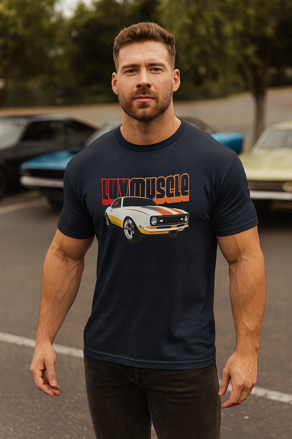 Man wearing a black bonspeed t-shirt with a muscle car graphic and text, standing in a parking lot with vintage cars.