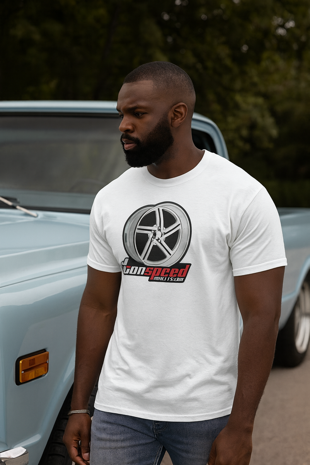 Man wearing a white bonspeed t-shirt with a logo in front of a classic car