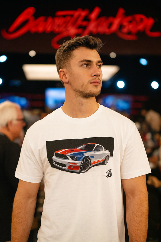 Man wearing a white bonspeed t-shirt with a Mustang car graphic at an event with 'Barrett-Jackson' sign.