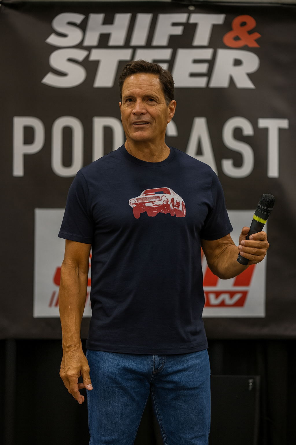 Man wearing a navy blue bonspeed t-shirt with a red graphic, holding a microphone in front of a 'Shift & Steer Podcast' banner.