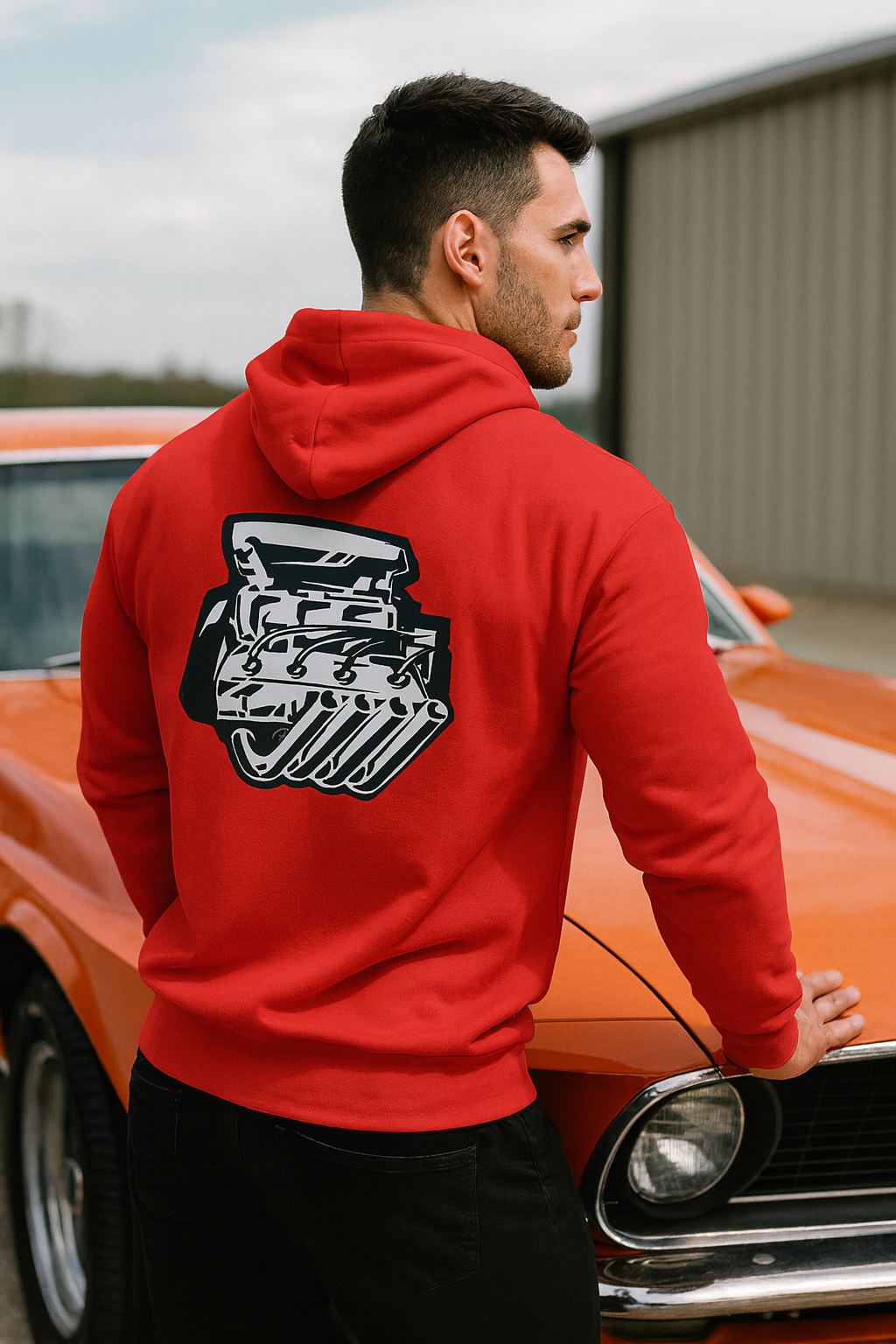 Man wearing a red bonspeed hoodie with a Hemi engine graphic, standing next to an orange car.